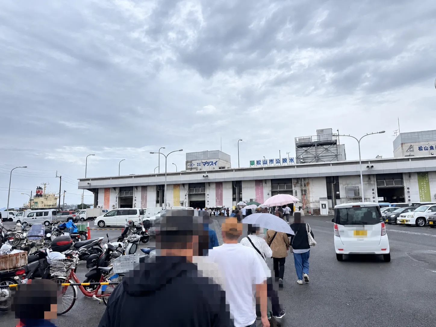 8時、小雨の中を市場の入口へ。傘を差す人の姿も。