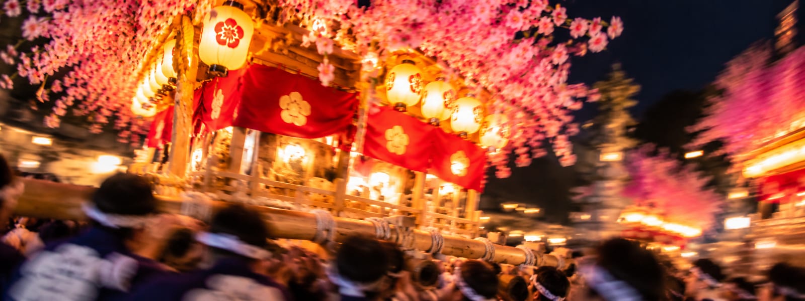 夜、提灯と花飾りを付けただんじりを担ぎ手が練るイメージ