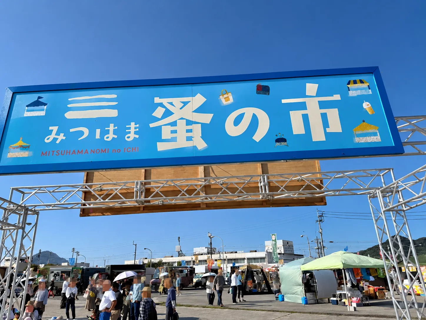 みつはま蚤の市の会場入口。青い看板の下を来場者が歩く様子